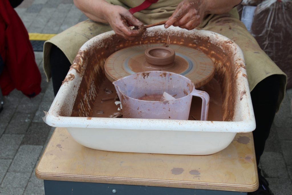 Hands turning clay on a wheel.