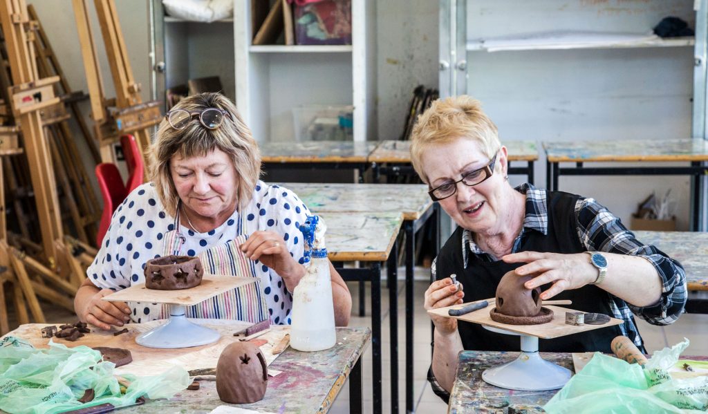Two people working together on their clay creations. 
