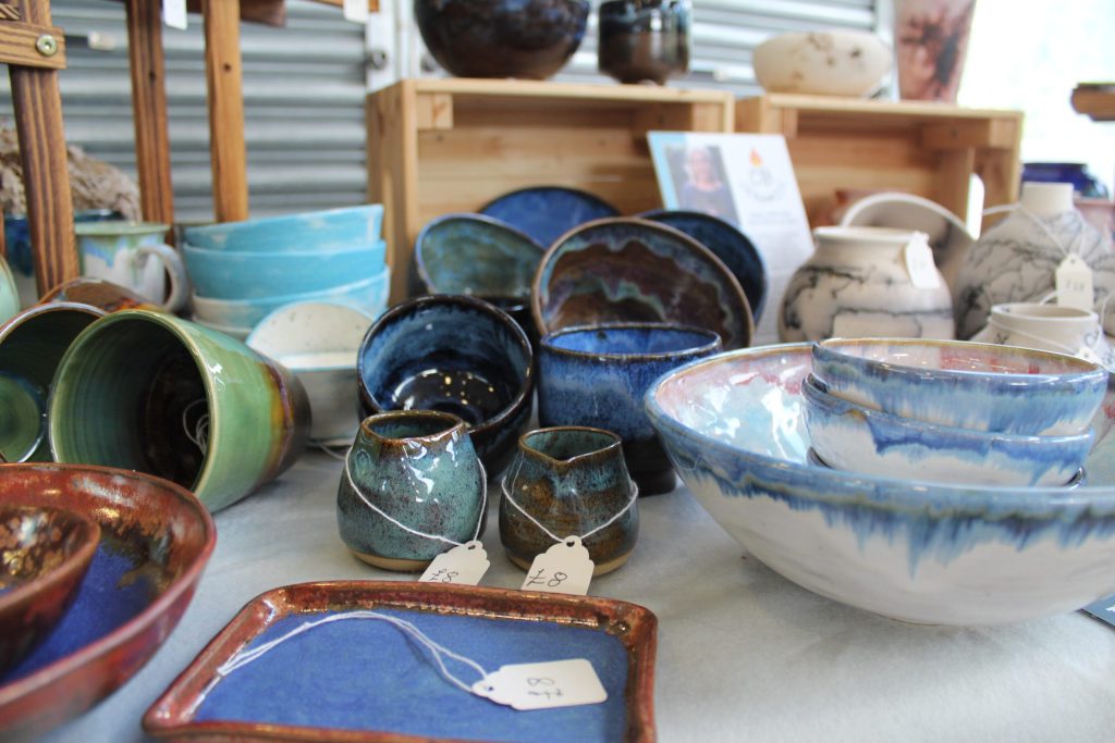 A table full of handmade ceramics in blues, greens, white and brown glazes.