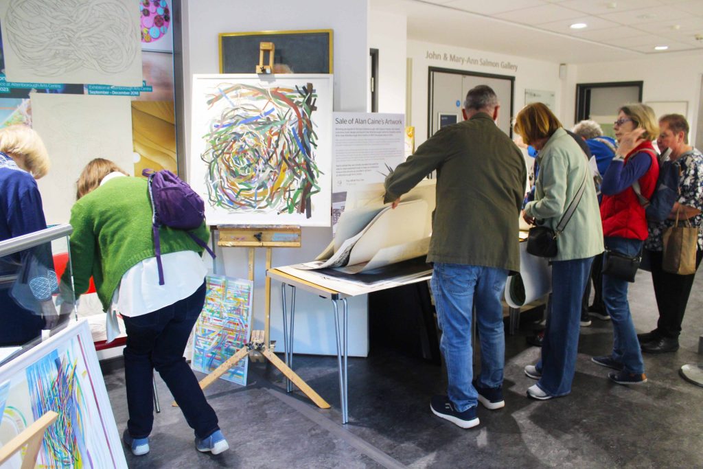 People looking through artwork on large sheets of paper.