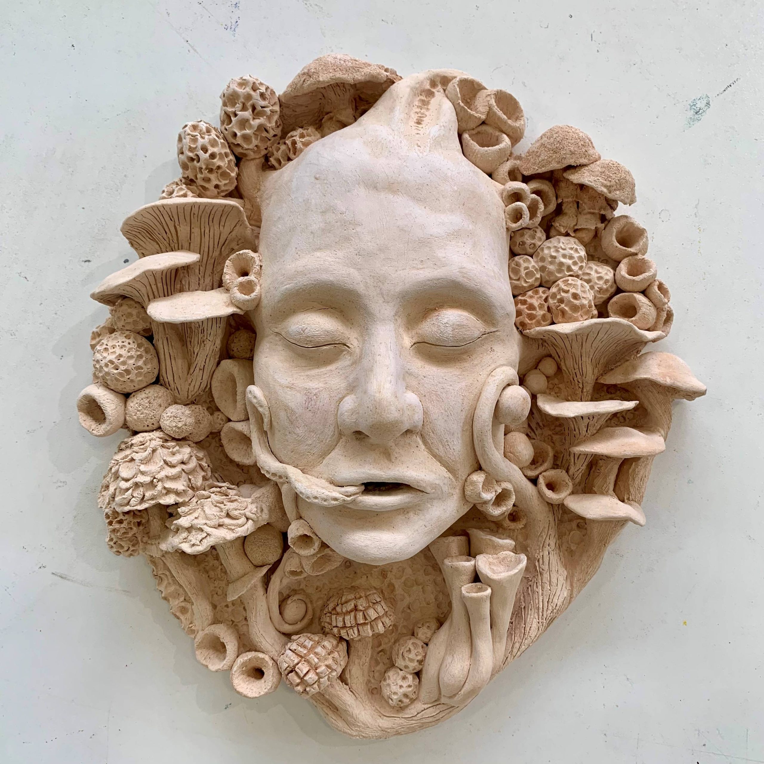 A sculpture of a head surrounded by fungi's and mushrooms.