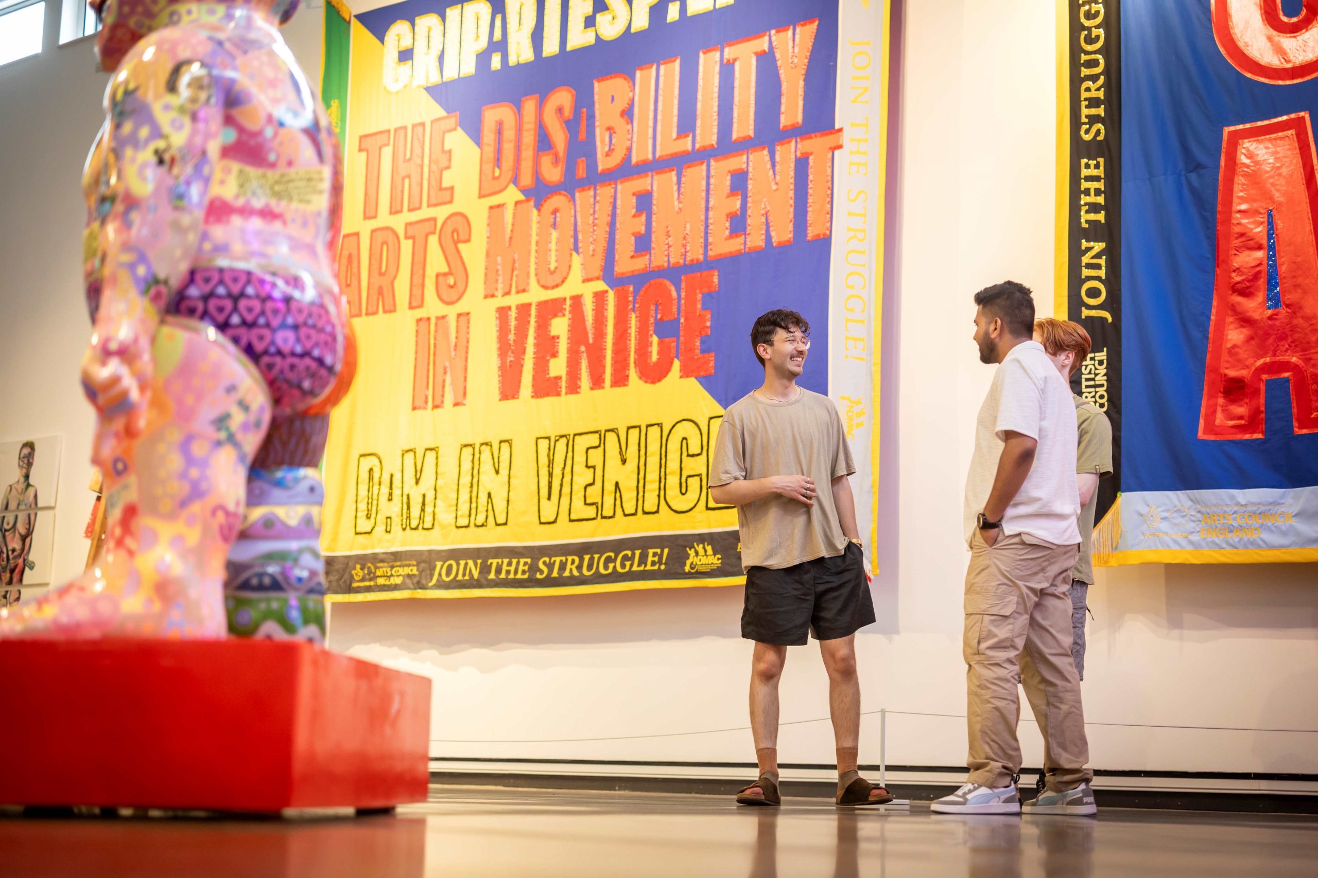 A group of young people chatting in a gallery surrounded by art.